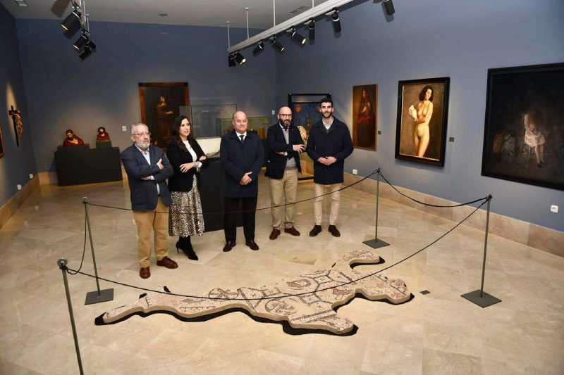 El alcalde de Antequera, Manolo Barón, la teniente de alcalde delegada de Turismo, Ana Cebrián, y el director del Museo de la Ciudad de Antequera, José Escalante, junto a otros miembros de la organización posan en el MVCA. Todos de pie en el centro de la sala, posan rodeados de obras, siendo una en el suelo el foco de interés.