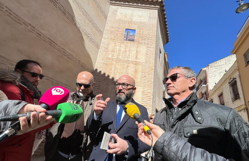 Algunos periodistas de televisión o de la radio entrevistan con sus micrófonos a miembros del ayuntamiento. Charlan afuera del edificio.